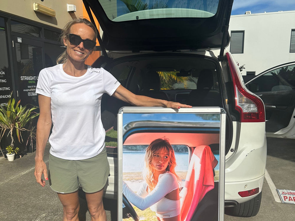 Vick standing by her open car boot with an Actv8 A-frame sign