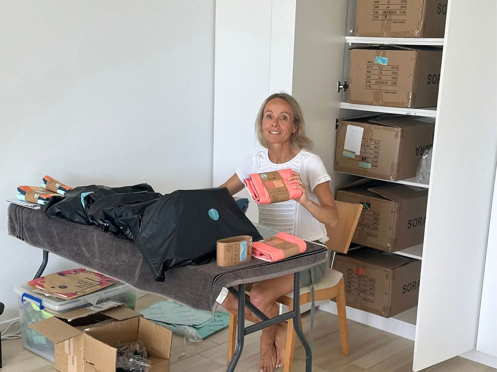 Vick packing orders at home, with cartons of stock on the shelves beside her