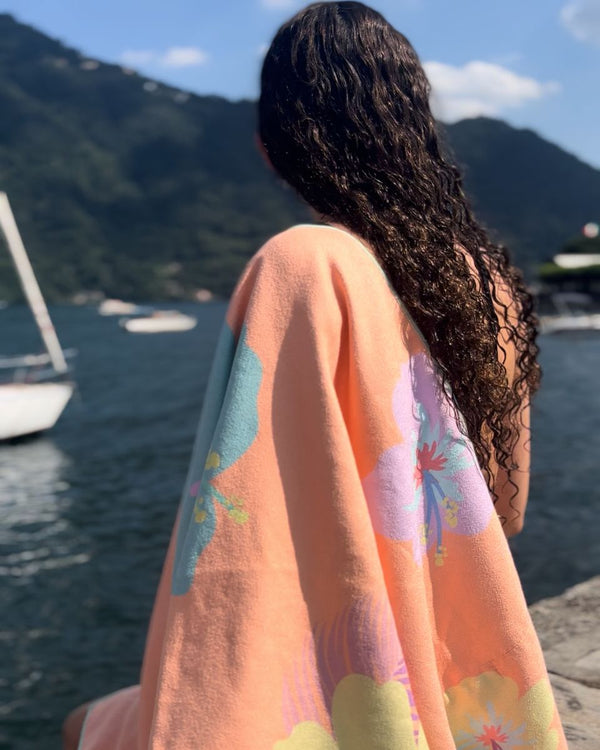 Woman with long curly hair wrapped in a floral towel beside a lake