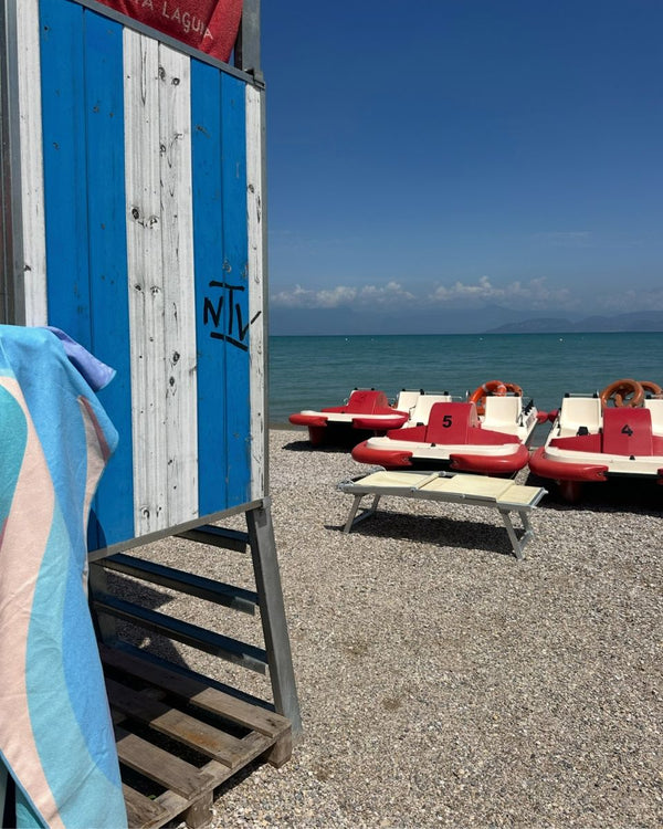 Striped towel hanging on a blue and white beach hut near pedal boats