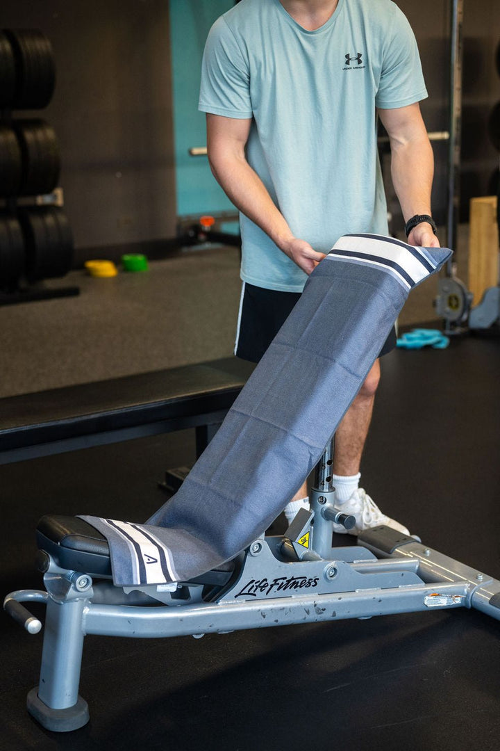Grey striped Actv8 gym towel being laid over a gym bench